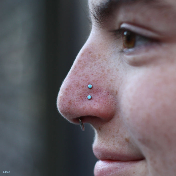 Two nostril piercings with Bezel-set Cabochon Press-fit Ends in Titanium from NeoMetal with 2mm turquoise